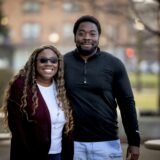 An African-American couple in a park under sunlight with a blurry background